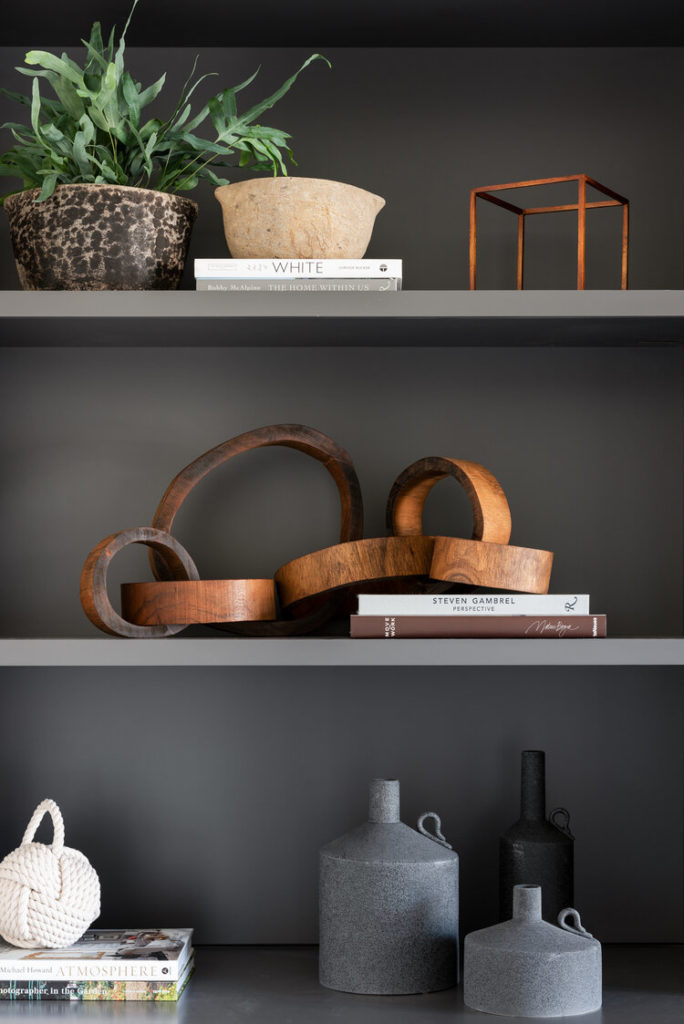 Wood and stone accessories on shelves in charcoal grey cabinet by Studio McGee