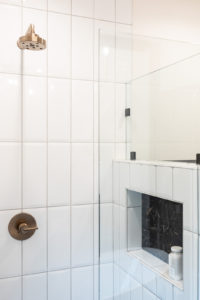 Tiled shower with built-in ledge for bottles.